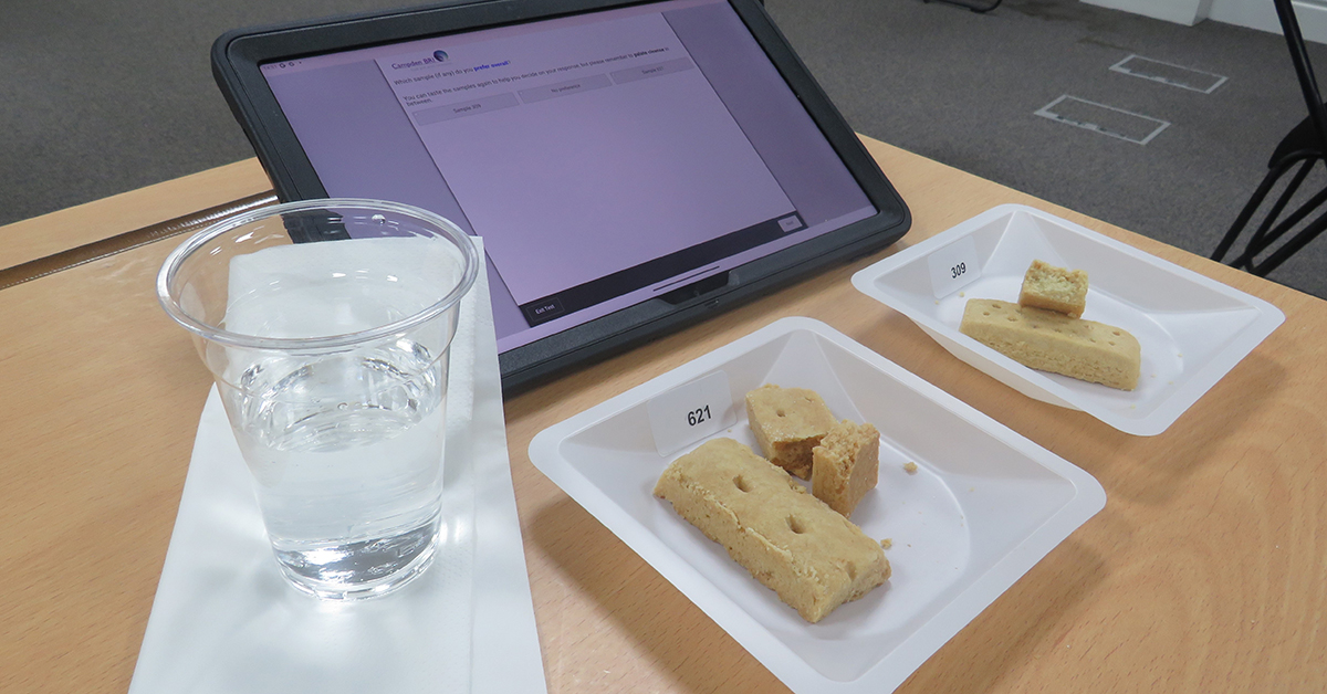 Consumer test setup with shortbread biscuits, electronic tablet and water on desk